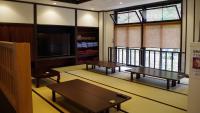 a room with tables and a tv and a balcony at Onsen Urashima in Onomichi