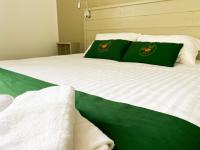 a bed with green and white sheets and green pillows at Colette Hôtel in Niort