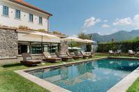 a pool with chairs and umbrellas next to a house at MUSA Lago di Como in Sala Comacina