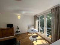 a living room with a table and chairs and a large window at Appartement de standing calme - Paris - Métro 9 in Montreuil