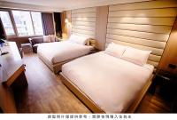 a hotel room with two beds and a window at Royal Group Hotel Minghua Branch in Kaohsiung