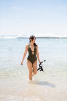 a woman in a bikini walking in the water at Hotel Renew in Honolulu