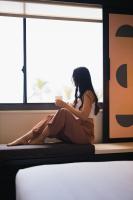 a woman sitting on a window sill with a cup of coffee at Hotel Renew in Honolulu