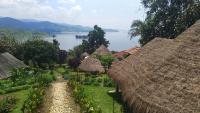 a group of straw huts with a view of a lake at INZU Lodge in Gisenyi