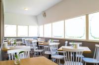 Un restaurante con sillas y mesas blancas y ventanas. en Hotel Pacific, en Roma