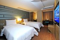 a hotel room with two beds and a flat screen tv at International Citizen Hotel in Kaohsiung