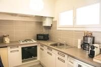 a kitchen with white cabinets and a sink and a microwave at L&#39;Escale - 2 Chambres balcon à 5 min des plages in Marseille