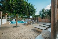 a pool with lounge chairs and a tree next to it at Coralli Seaside Resort in Livadakia