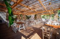 a row of tables and chairs under a wooden pergola at Coralli Seaside Resort in Livadakia