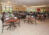 una sala da pranzo con tavoli e sedie in legno di Flat em Franca SP a Franca