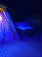 a bath tub sitting on a deck at night at Au-Doux-Altic chalet romantique avec JACUZZI ET SAUNA in Métabief