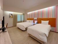 a hotel room with two beds and a flat screen tv at Jia Hsin Garden Hotel in Tainan