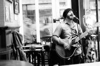Ein Mann spielt Gitarre in einem Zimmer in der Unterkunft Durty Nelly&#39;s Inn in Amsterdam