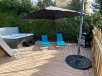 a patio with two chairs and an umbrella and a tub at Au-Doux-Altic chalet romantique avec JACUZZI ET SAUNA in Métabief