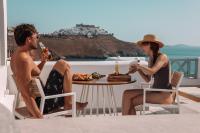 a man and a woman sitting at a table with drinks at Infinity Blue Boutique Hotel Astypalaia in Astypalaia Town