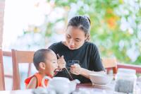 een vrouw zit aan tafel met een jongen en eet samen bij Star Hill Village Resort Phu Quoc in Phu Quoc