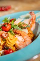 een blauwe plaat met garnalen en pasta bij Elbstrand Resort Krautsand in Drochtersen