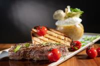 een biefstuk op een bord met tomaten en brood bij Elbstrand Resort Krautsand in Drochtersen