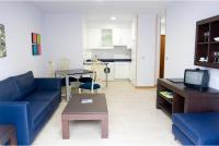 Una sala de estar con un sofá azul y una mesa. en Apartamentos Turisticos Noray, en Argoños