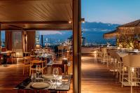 Un restaurante con mesas y sillas en un balcón. en Brown Acropol, a member of Brown Hotels, en Atenas