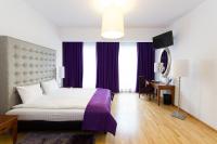 Schlafzimmer mit einem großen Bett mit lila Vorhängen und einem Schreibtisch in der Unterkunft Don Prestige Residence in Posen