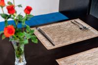 a table with a vase of roses and a napkin and fork and knife at Nature Boutique Hotel - Nguyen Thi Nghia in Da Lat