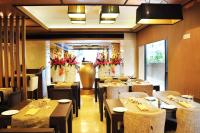 a restaurant with tables and chairs and a large vase at Hotel Senses in Kolkata