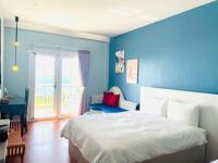 a bedroom with blue walls and a bed and a desk at Canaan B&amp;B Kenting in Eluan