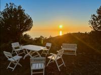 a table and chairs with the sunset in the background at Domaine de la coletta Maison traditionnelle in Coti-Chiavari