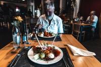 un hombre sentado en una mesa con dos platos de comida en Hotel Cornelyshaff, en Heinerscheid