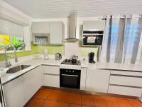 a kitchen with white cabinets and a sink at Villa Paradis in Le François
