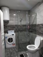 a bathroom with a shower and a toilet and a washing machine at Twins Apartments in Čačak