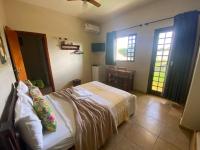 a bedroom with a bed and two windows at Chico de Sá Pousada in Pirenópolis
