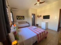 a bedroom with a bed and a couch and a tv at Chico de Sá Pousada in Pirenópolis