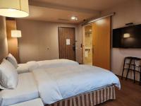 a hotel room with two beds and a flat screen tv at Kindness Hotel - Kaohsiung Main Station in Kaohsiung