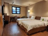 a hotel room with two beds and a desk at Kindness Hotel - Kaohsiung Main Station in Kaohsiung