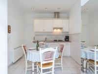 a kitchen with white cabinets and a table with chairs at Apartment Le Chalet by Interhome in Cabourg