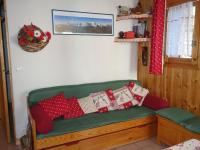 a green couch with red and white pillows on it at Apartment Les Jardins Alpins-9 by Interhome in Saint-Gervais-les-Bains