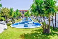 a swimming pool in a park with palm trees at Skiathos Holiday Resort in Skiathos