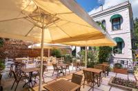 Un patio al aire libre con mesas, sillas y sombrillas. en Büyükada Anastasia Meziki History Mansion, en Büyükada