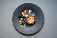 a black plate with a piece of meat and vegetables at Bellevue Parkhotel & Spa - Relais & Châteaux in Adelboden