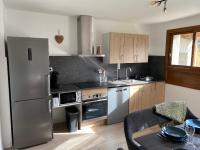 a kitchen with a stainless steel refrigerator and a table at Appartement Le Lauzet in La Roche-de-Rame