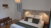a bedroom with a large bed with green and white pillows at Le 14 Faubourg in Beaune