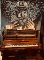 ホニングスヴォーグにあるArctic Boutique Hotel Northcapeの壁に絵が飾られた古いピアノ