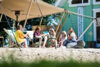 Chalet aan het water - vakantiepark de Schreiershoek في دوكوم: مجموعة من الناس يجلسون على الكراسي على الشاطئ