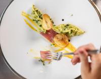 a person eating food on a plate with a fork at Cyprianerhof Dolomit Resort in Tires