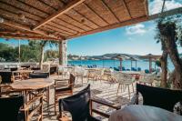 a restaurant with tables and chairs and the ocean in the background at Coralli Seaside Resort in Livadakia