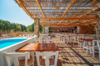 a patio with tables and chairs next to a pool at Coralli Seaside Resort in Livadakia