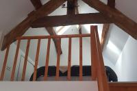 a wooden staircase with a black couch in a room at Maison La Plage cadre verdoyant et calme in Port-Mort