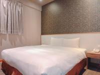 a bedroom with a large white bed and a telephone at Centre Hotel in Kaohsiung